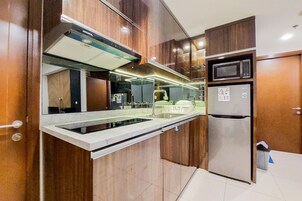 Una cocina moderna con microondas integrado, refrigerador de acero inoxidable y una encimera elegante.