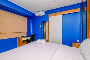 Une chambre d’hôtel avec un lit, un bureau, une chaise et une armoire.