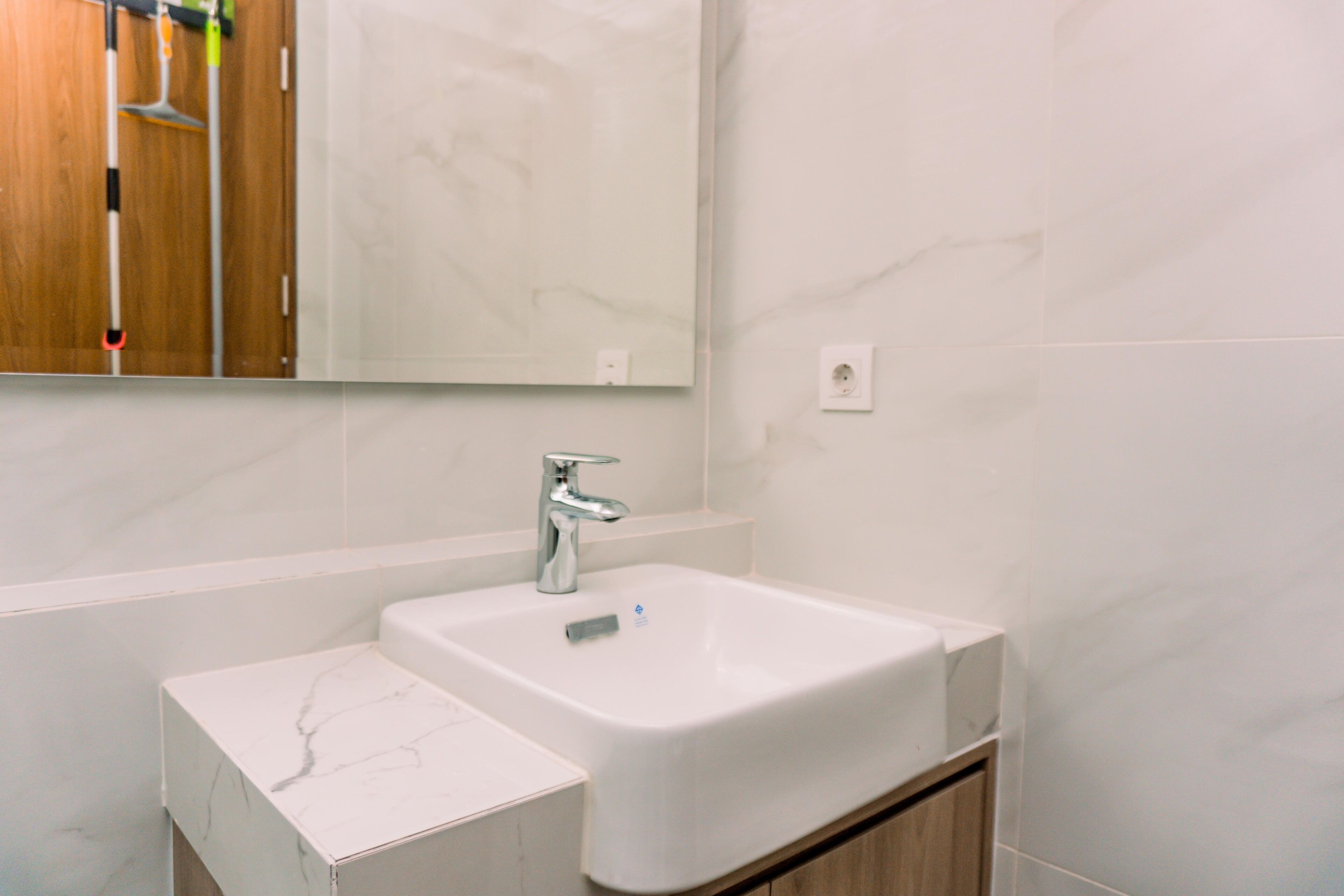 A bathroom with a white sink, a mirror, and a wooden cabinet.