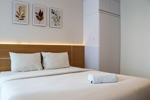 A neatly made bed with white linens and pillows, a wooden headboard, and three framed leaf artworks on the wall. - Elegant And Comfy Studio At Tamansari Iswara Apartment (Bekasi)