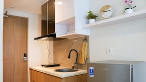 A compact kitchen with a sink, a stove, and a refrigerator. - Elegant And Comfy Studio At Tamansari Iswara Apartment (Bekasi)