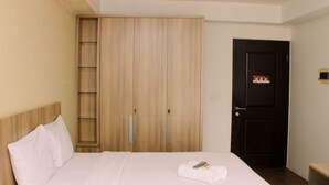 A hotel room with a bed, a wardrobe, and a door. - Cozy Studio At Metropark Condominium Jabebeka Apartment (Cikarang)