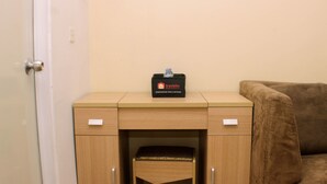 A small wooden desk with a travel bag labeled 'Travelio' and a cushioned stool underneath. - Cozy Studio At Metropark Condominium Jabebeka Apartment (Cikarang)