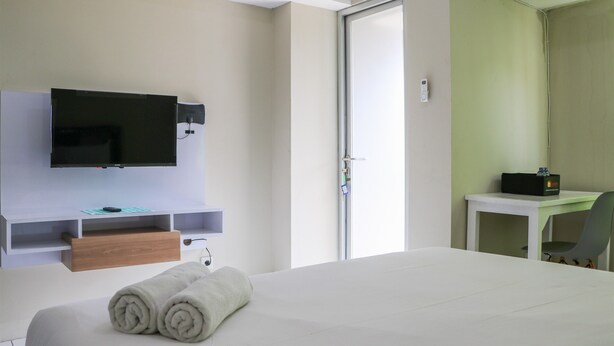 Habitación de hotel con cama, televisor montado en la pared, escritorio y silla, y una puerta.