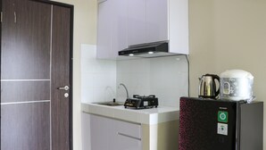 Una cocina compacta con microondas, hervidor y cafetera sobre una encimera.