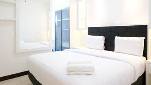 A hotel room with a large bed, a black headboard, white bedding, and a window with a view. - Spacey And Homey 2Br At Supermall Mansion Apartment (Surabaya)