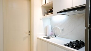 A modern kitchen with white cabinets, a stainless steel range hood, a marble backsplash, and a built-in oven. - Spacey And Homey 2Br At Supermall Mansion Apartment (Surabaya)