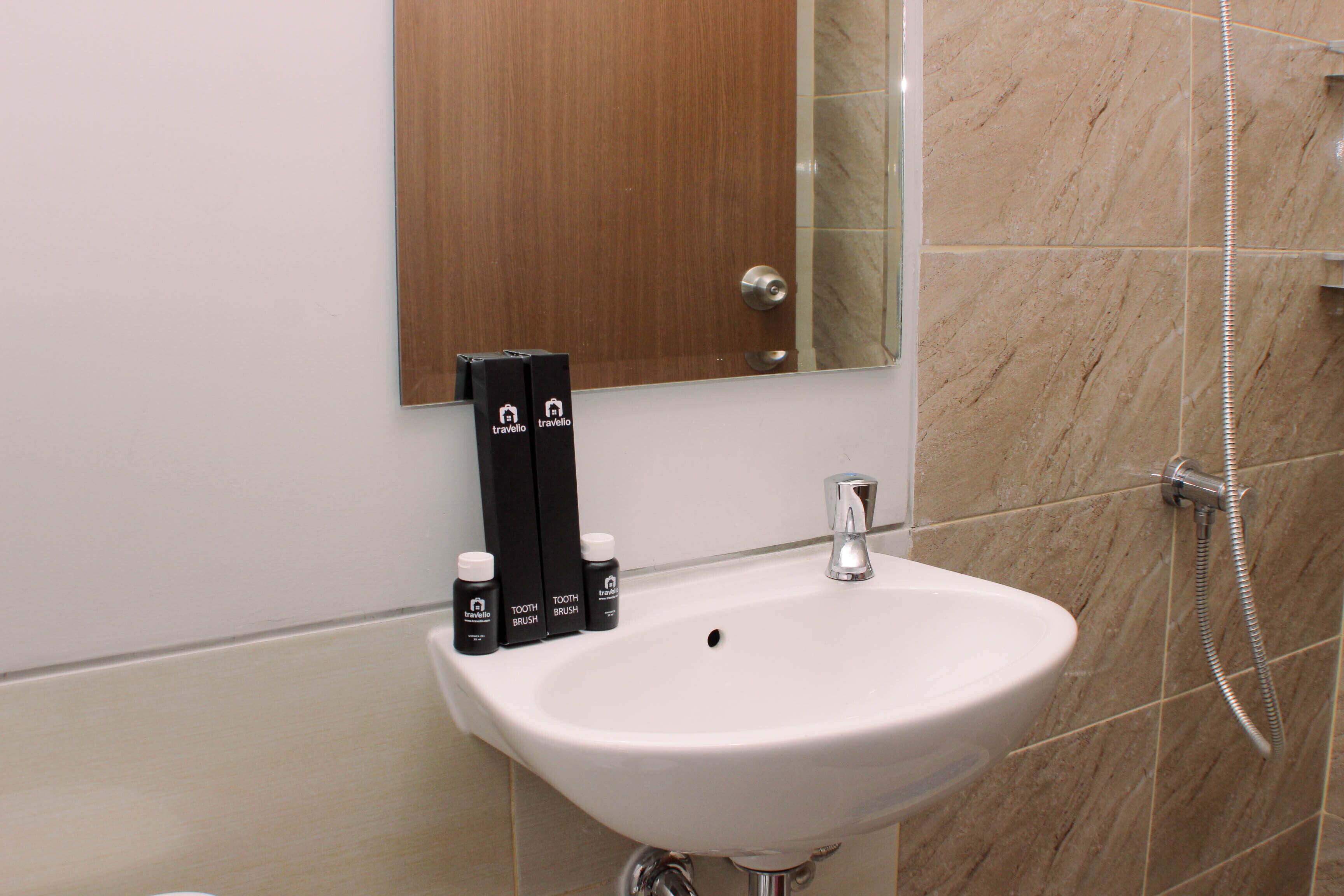 Un bagno con un lavandino bianco, uno specchio sopra e uno spazio doccia.