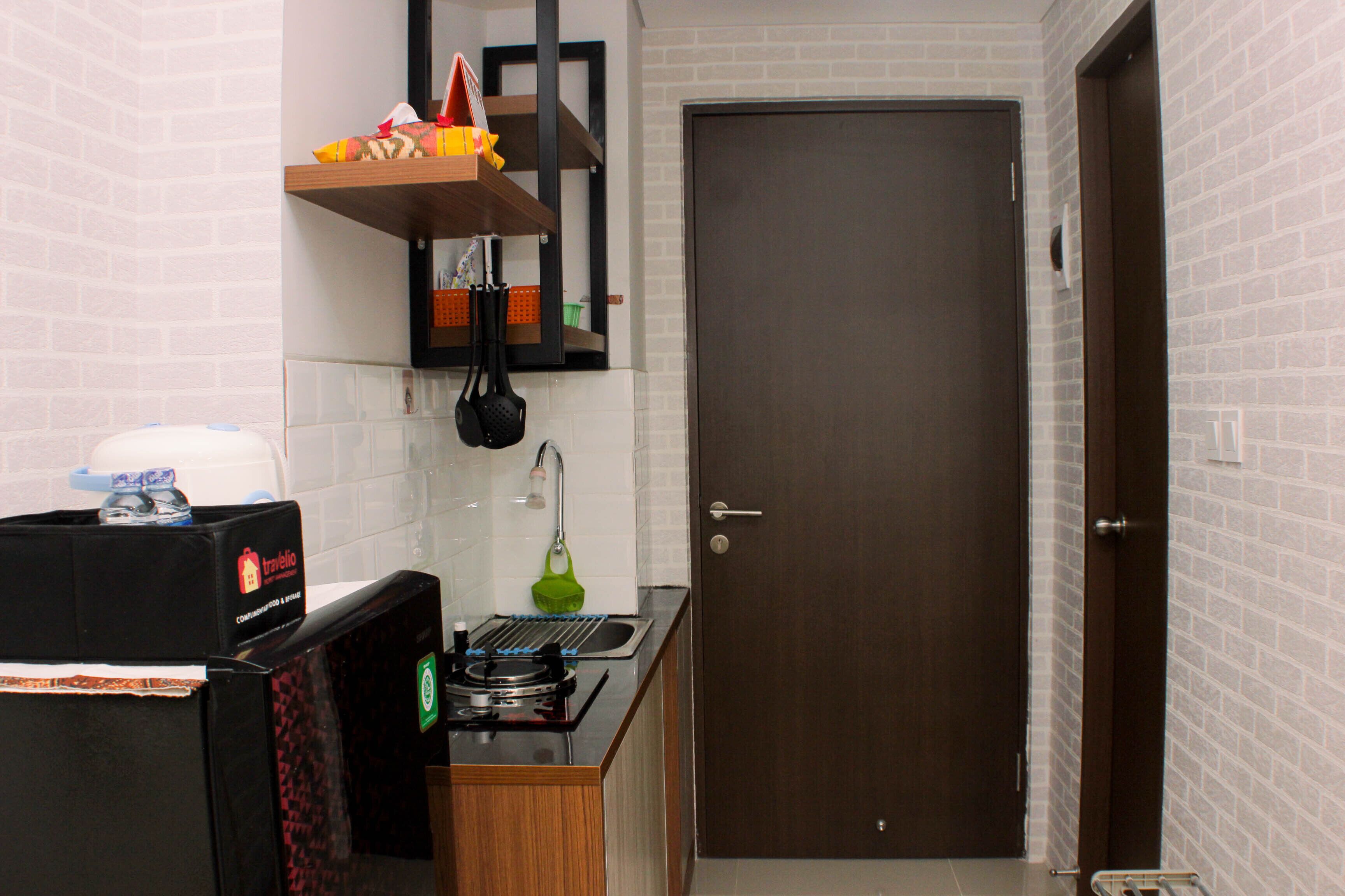 A compact kitchen with a microwave, a small sink, and a door leading to another room.