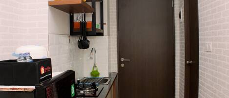 A compact kitchen with a microwave, a small sink, and a door leading to another room.