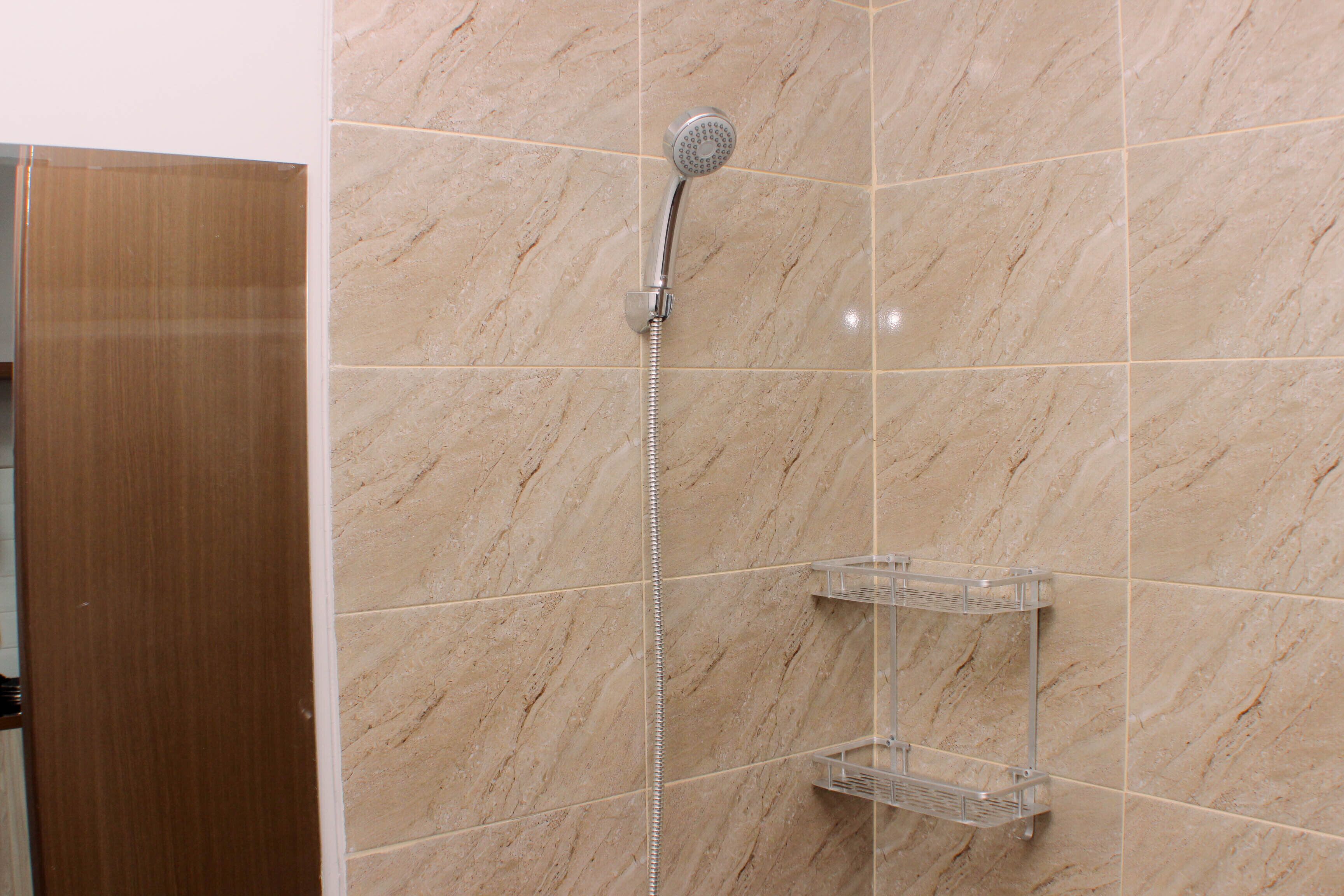 A bathroom with a shower, marble tiles, and a wooden door.