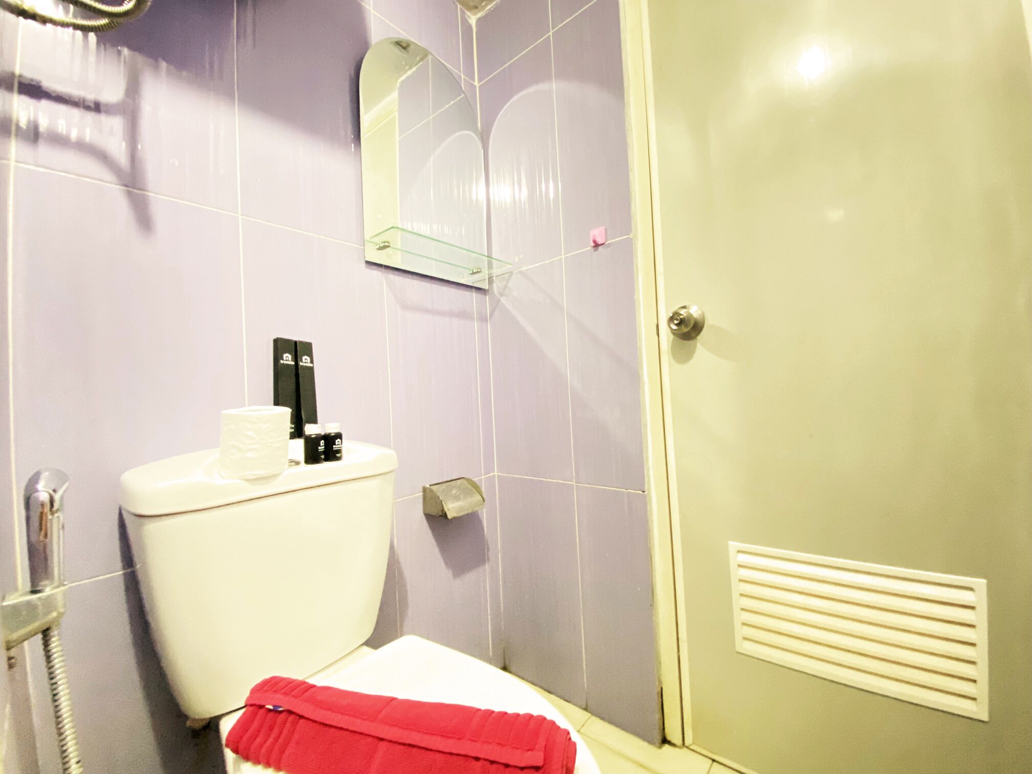 Un baño con inodoro, ducha y espejo.