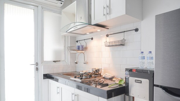 A modern kitchen with white cabinets, a stainless steel refrigerator, and a water dispenser. - Cozy And Tidy 1Br At Kebagusan City Apartment (Jakarta)