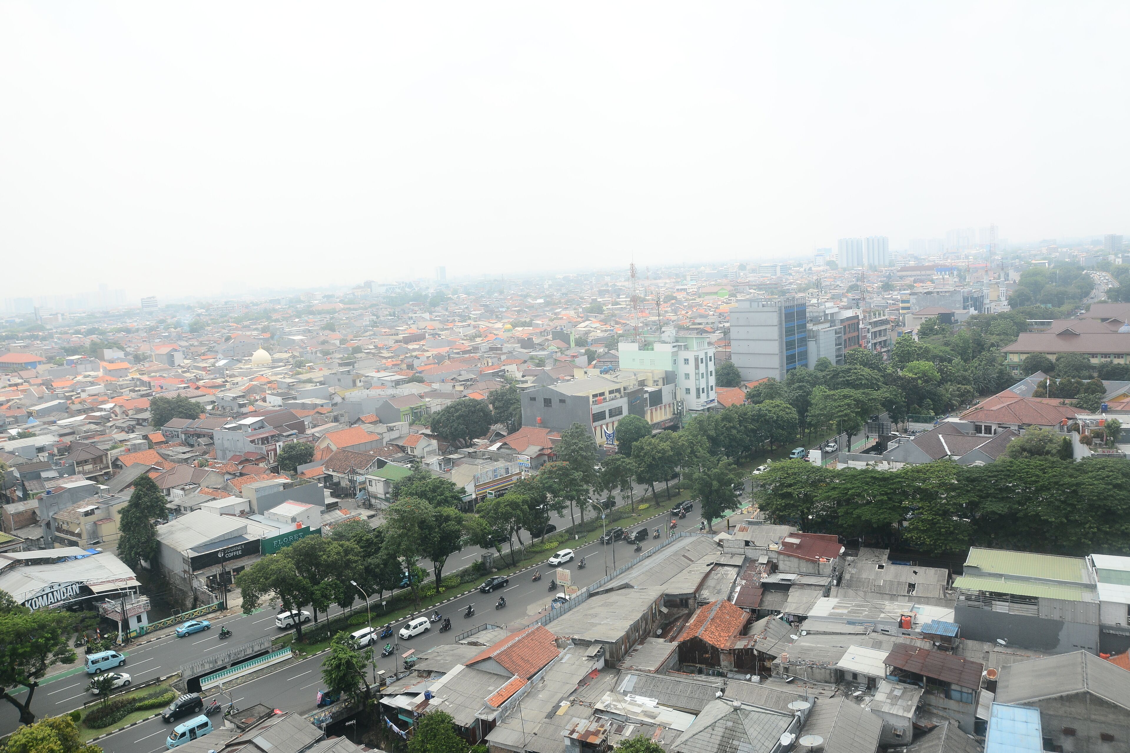 A cityscape with a mix of residential and commercial buildings, a wide street, and a clear view of the surrounding urban area.