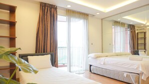 A hotel room with a bed, a bedside table, a mirror, and a view of the outside balcony. - Spacious And Homey 2Br At Nuasa Hijau Pondok Indah Apartment (Jakarta)