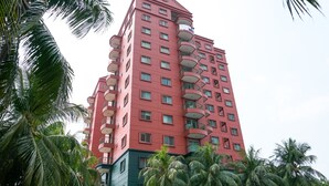 A multi-story hotel with balconies, surrounded by palm trees. - Spacious And Homey 2Br At Nuasa Hijau Pondok Indah Apartment (Jakarta)