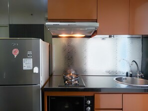 Uma cozinha compacta com geladeira, fogão a gás e pia.