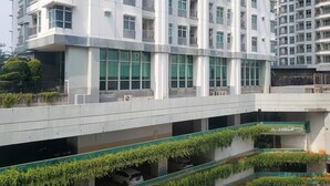 A multi-story residential building with balconies, large windows, and a covered parking area with greenery. - Nice And Cozy Living 2Br Apartment At Green Bay Pluit (Jakarta)