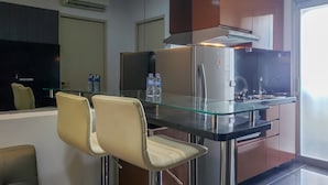 A modern kitchen with a glass-top bar, stainless steel appliances, and a view of the outside. - Nice And Cozy Living 2Br Apartment At Green Bay Pluit (Jakarta)