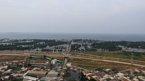 An aerial view of a coastal town with a mix of residential and commercial buildings, a prominent bridge, and a body of water in the distance. - Cozy Living Studio Apartment At High Floor Tokyo Riverside Pik 2 (Teluknaga)