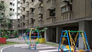 Un terrain de jeux avec des balançoires et une structure d’escalade, situé en milieu urbain.