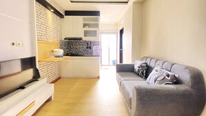 Un salon moderne avec un canapé gris et un téléviseur à écran plat.