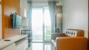 Una sala de estar moderna con un televisor de pantalla plana montado en la pared, un sofá, una mesa de centro y un balcón con ventana corredera.