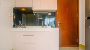 Una cocina compacta con campana extractora de acero inoxidable, pileta integrada y puerta de madera.