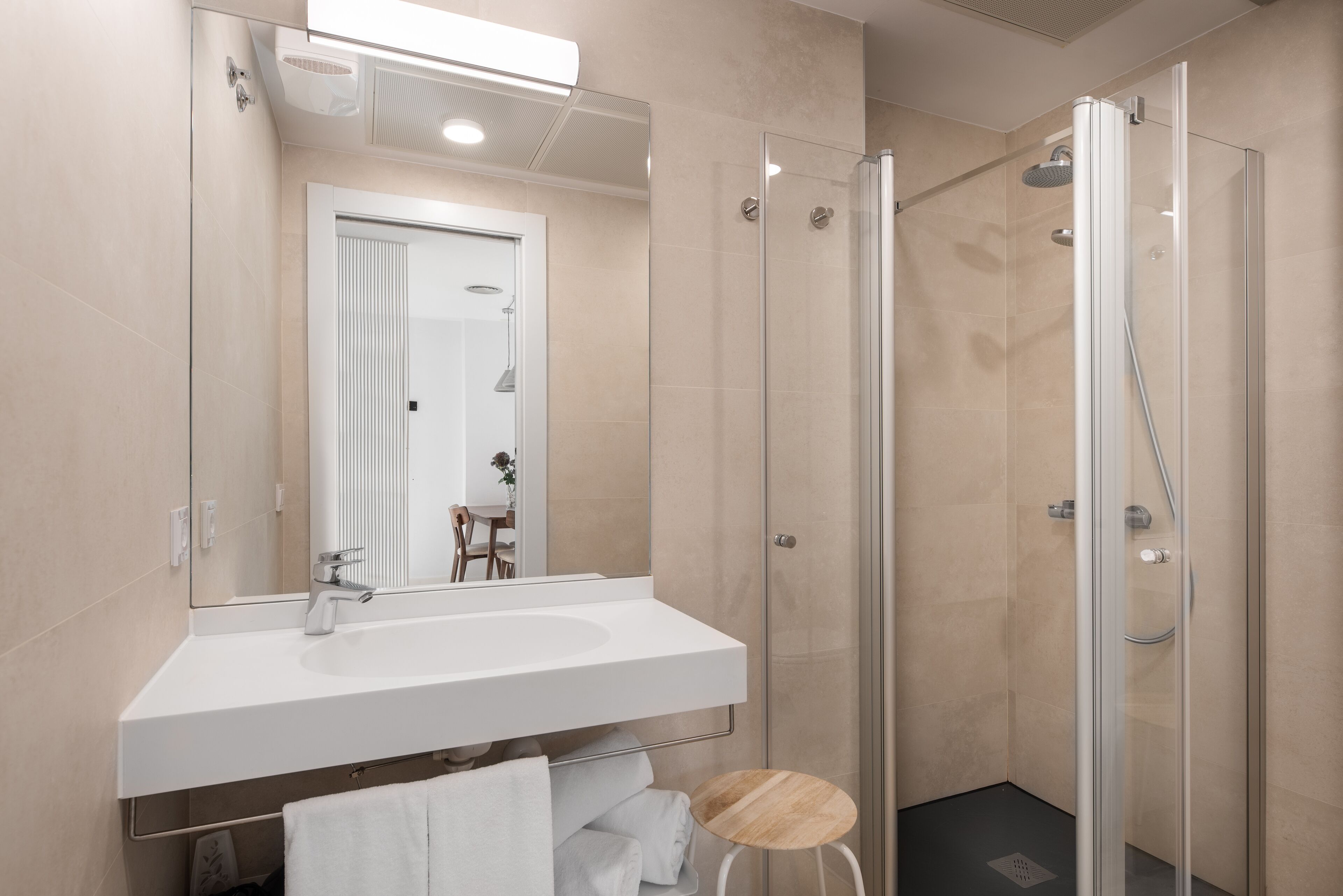 A modern bathroom with a glass-enclosed shower, a white sink, and a mirror above the sink.