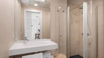 A modern bathroom with a glass-enclosed shower, a white sink, and a mirror above the sink.
