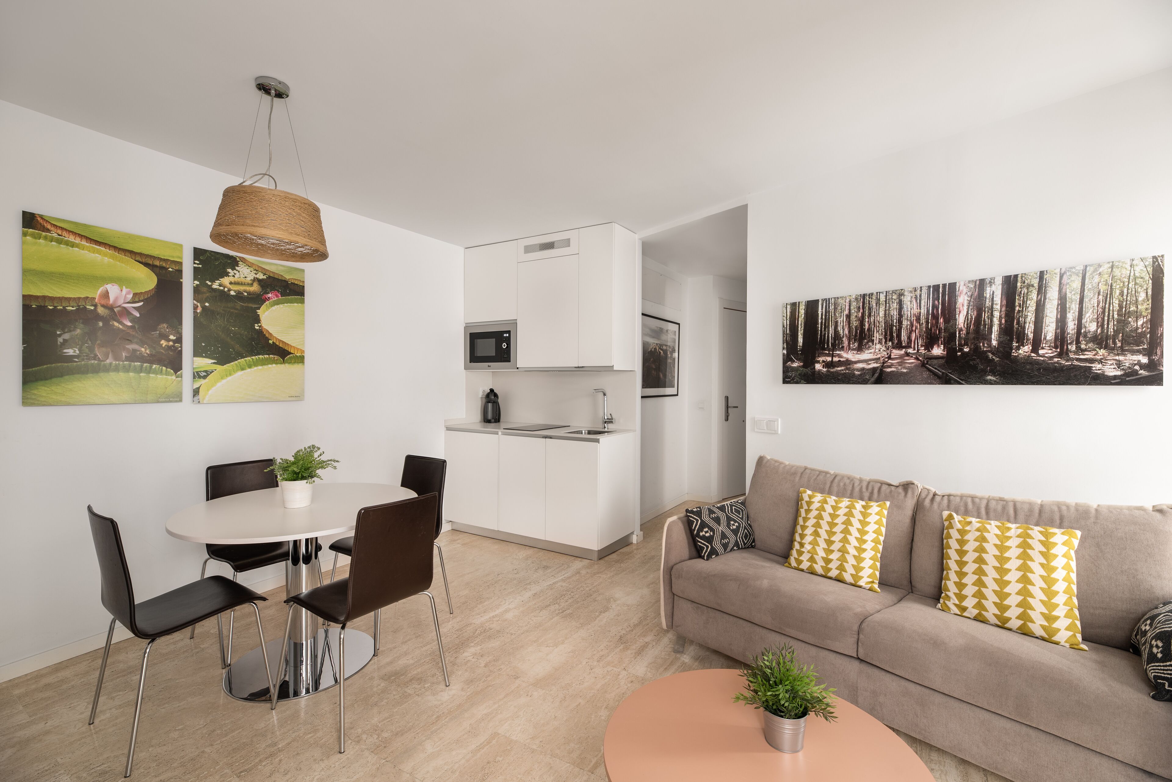 A modern living space with a dining area, kitchenette, and a sofa with patterned cushions.