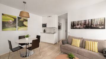 A modern living space with a dining area, kitchenette, and a sofa with patterned cushions.