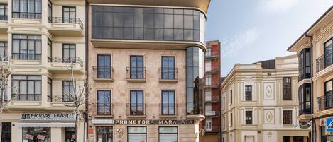 A multi-story building with a prominent curved glass facade, a ground-floor entrance, and several balconies.