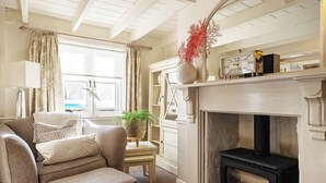 Un salon chaleureux avec une cheminée, un canapé, une lampe et une fenêtre avec des rideaux.