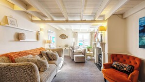 Un salon chaleureux avec un canapé à motifs chevrons, un fauteuil capitonné et un fauteuil orange vif.