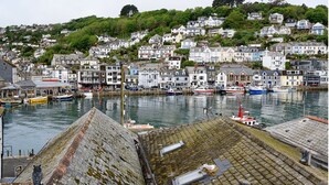 Une ville côtière dotée d’un port, de maisons construites sur une colline et de bateaux amarrés dans l’eau.
