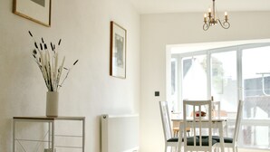 A bright room with a dining table and chairs, a radiator, and a vase with plants. - The Manhattan A Boutique Hotel By American Ease (Grafenwohr)