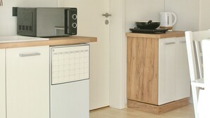 A compact kitchen with a microwave, a small refrigerator, a coffee maker, and wooden cabinets. - The Manhattan A Boutique Hotel By American Ease (Grafenwohr)
