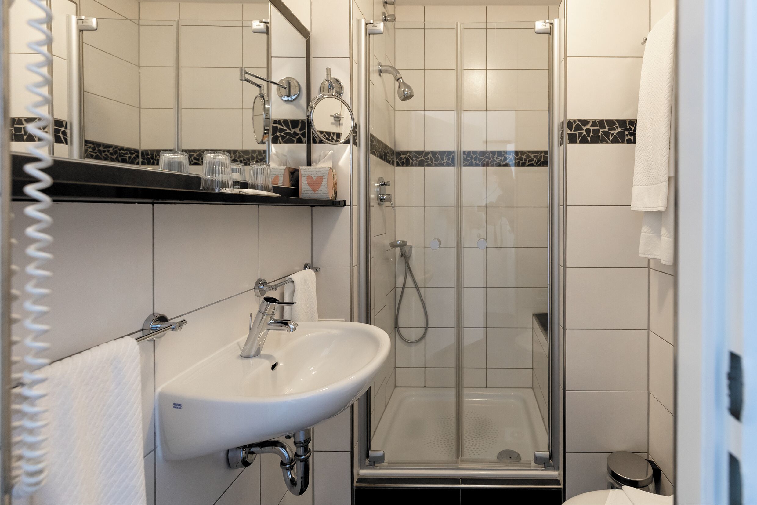A bathroom with a glass-enclosed shower, a white sink, and a mirror above the sink.