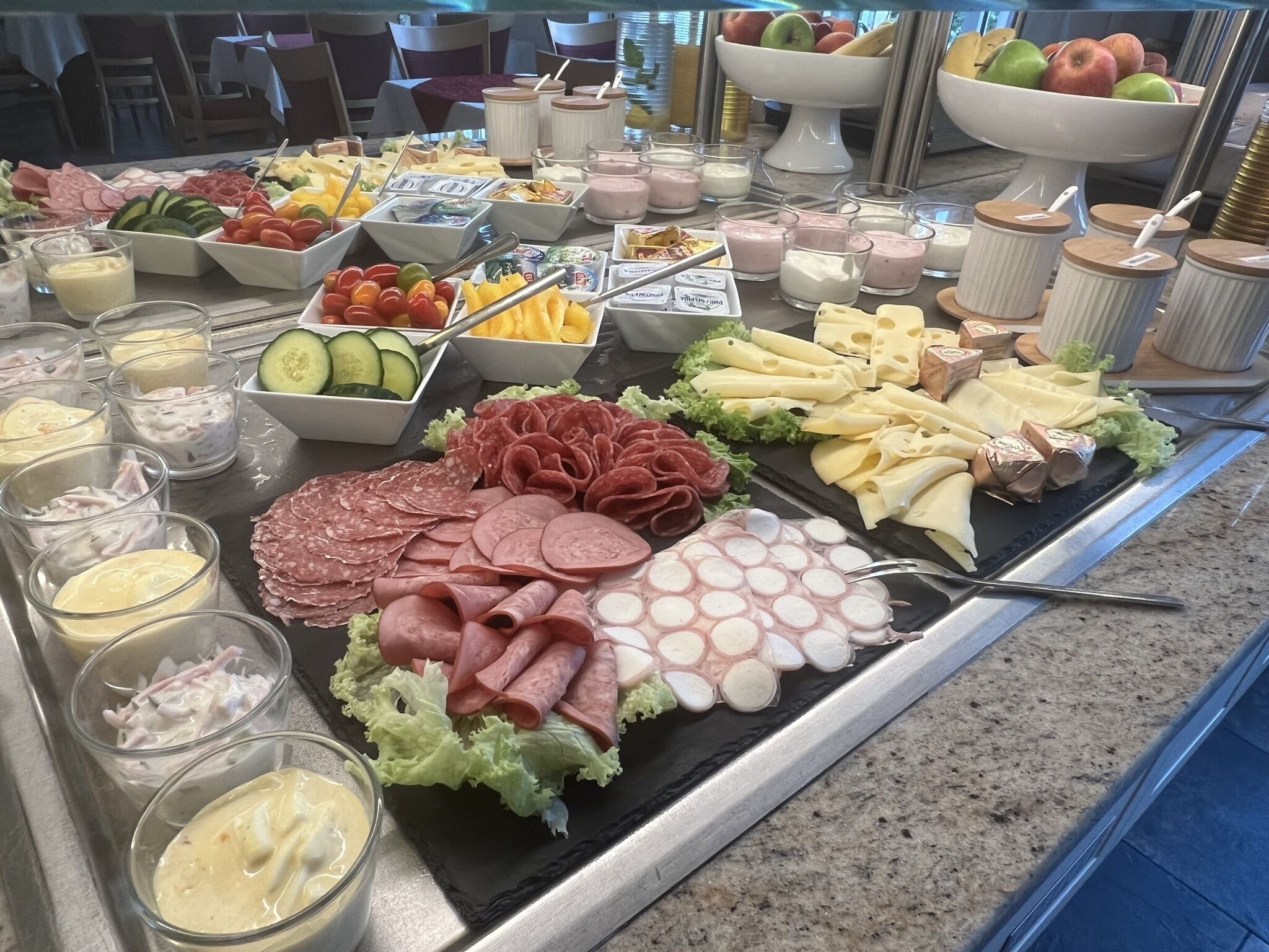 A buffet with various food items including meats, cheeses, fruits, and dips.