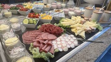 A buffet with various food items including meats, cheeses, fruits, and dips.
