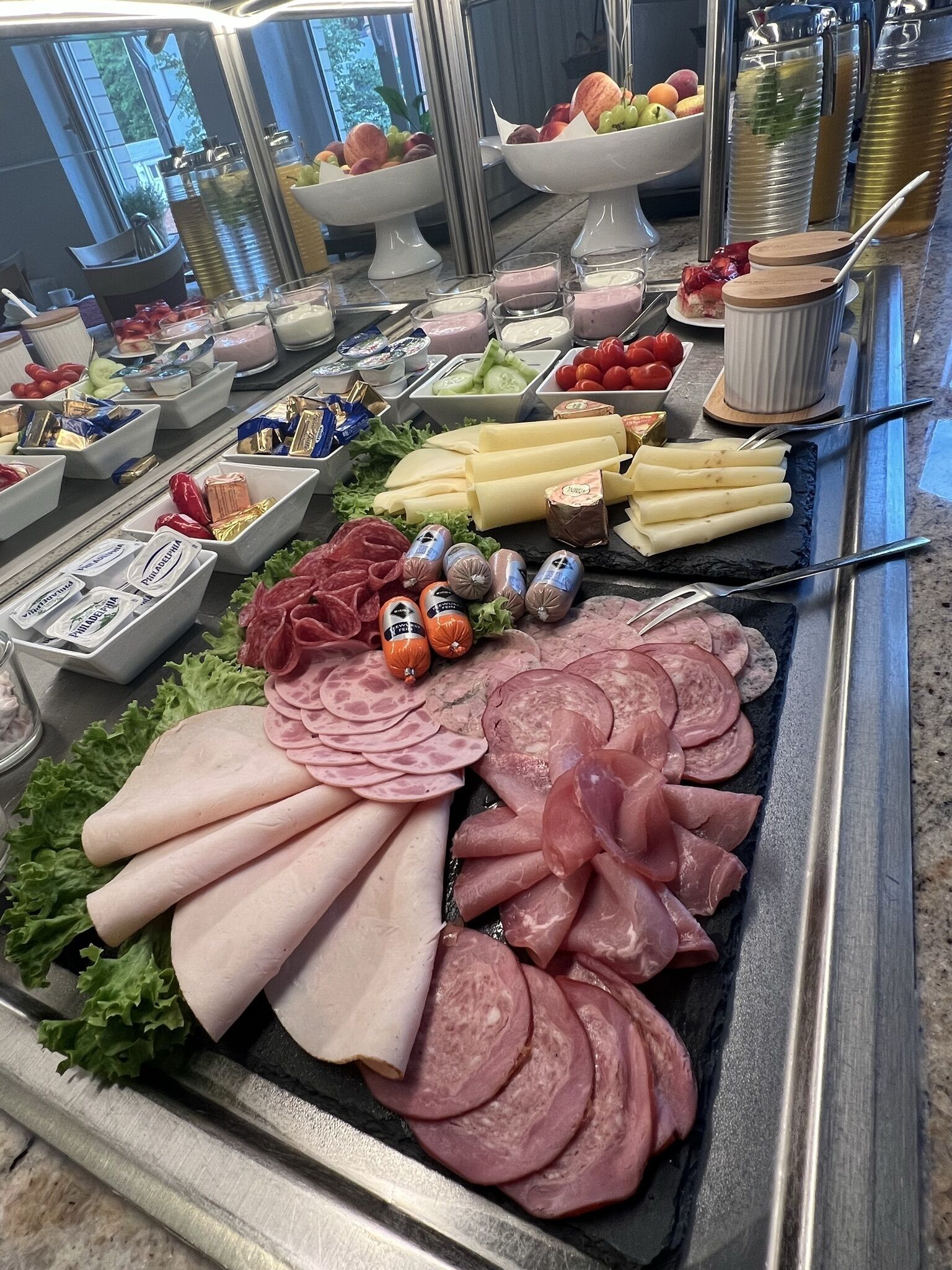 A buffet with various meats, cheeses, and fruits.