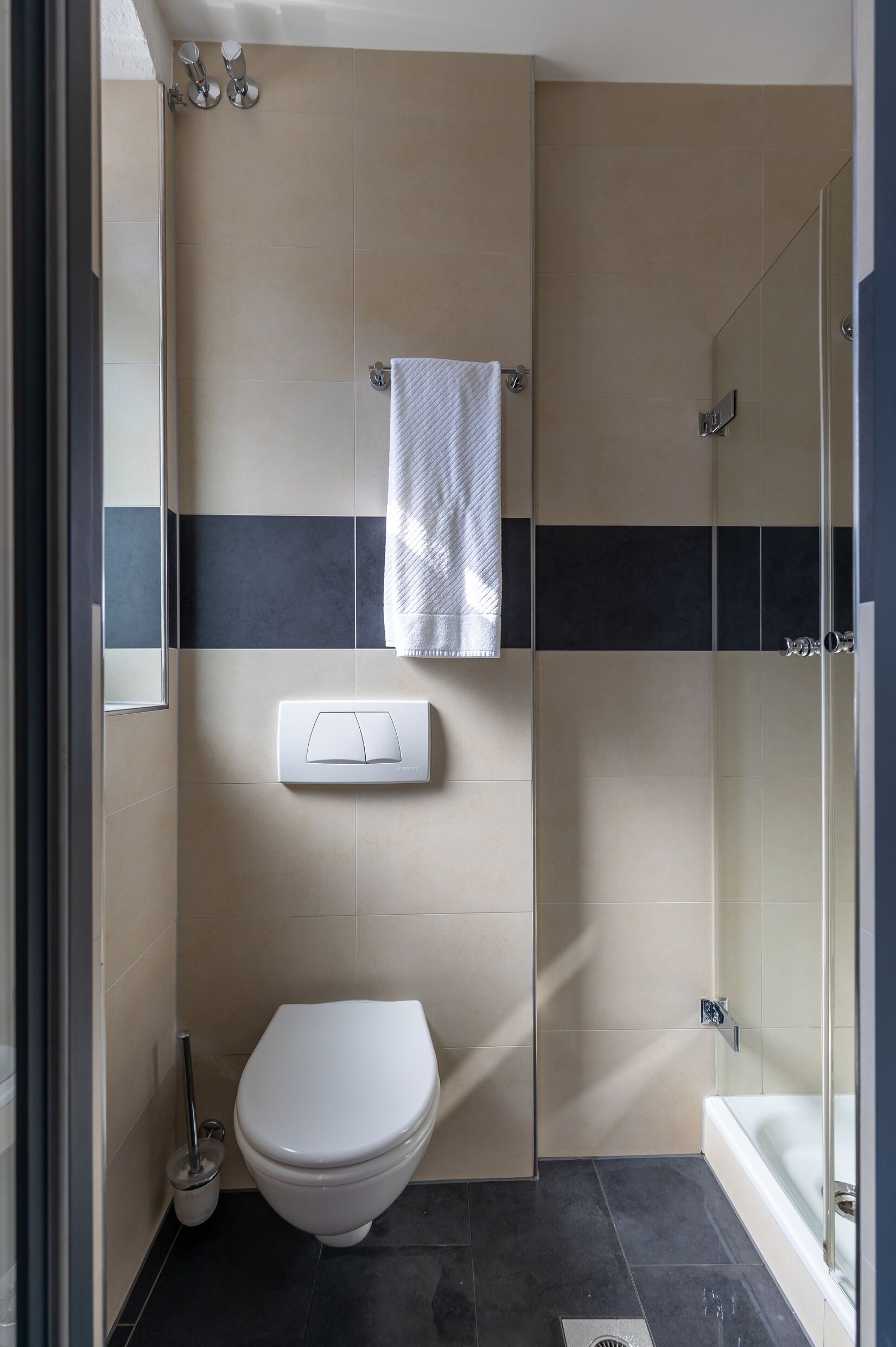 Ein modernes Badezimmer mit Toilette, Handtuchhalter, Dusche und einer Duschkabine.