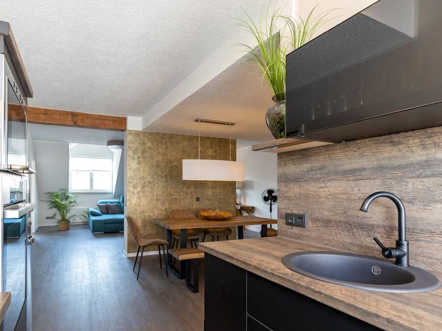 A modern kitchen with a wooden countertop, a sink, and a dining area with a table and chairs.