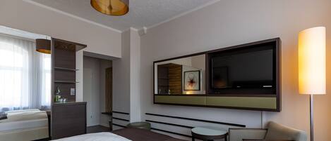 Una habitación de hotel moderna con una cama grande, un televisor de pantalla plana, un escritorio y un área de descanso.