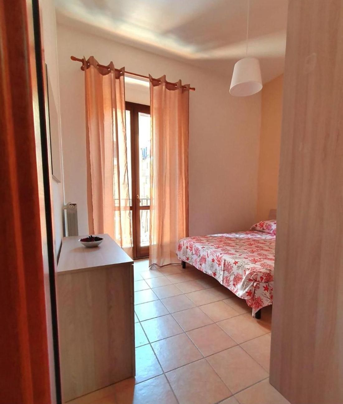 Un dormitorio con una cama, un escritorio y una ventana con cortinas.