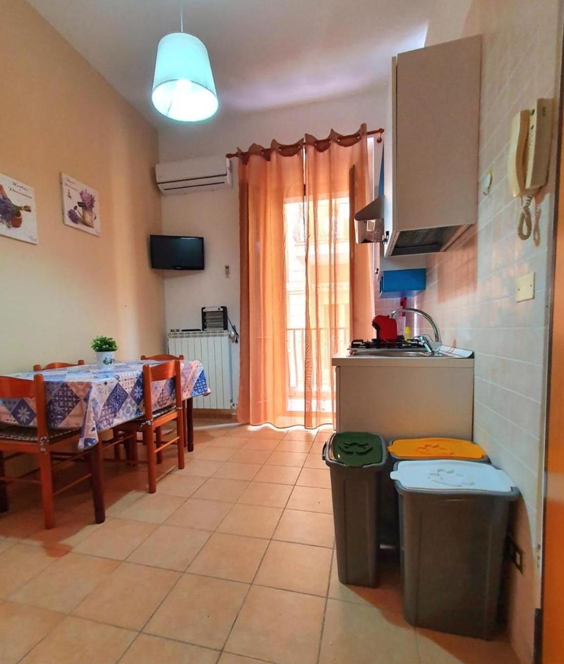 Espaço compacto com área de jantar, cozinha compacta e uma cama de solteiro.