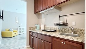 A modern kitchen with wooden cabinets, a granite countertop, and a stainless steel sink. - Room in House - Cheerful And Cozy one Large Bedroom (Jurupa Valley)