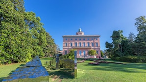 A large building with a central dome and symmetrical windows, surrounded by well-maintained grass and trees. - Via al Chioso Apartments (Lugano)