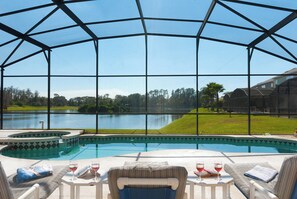 A pool area with a view of a lake, surrounded by a covered patio with seating and a table. - 5 Bedroom Executive Home - Private Pool and Spa (Davenport)